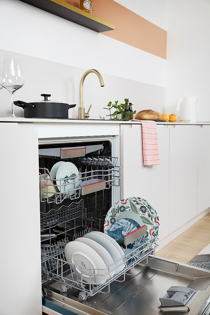 An open built-in dishwasher in a white kitchen