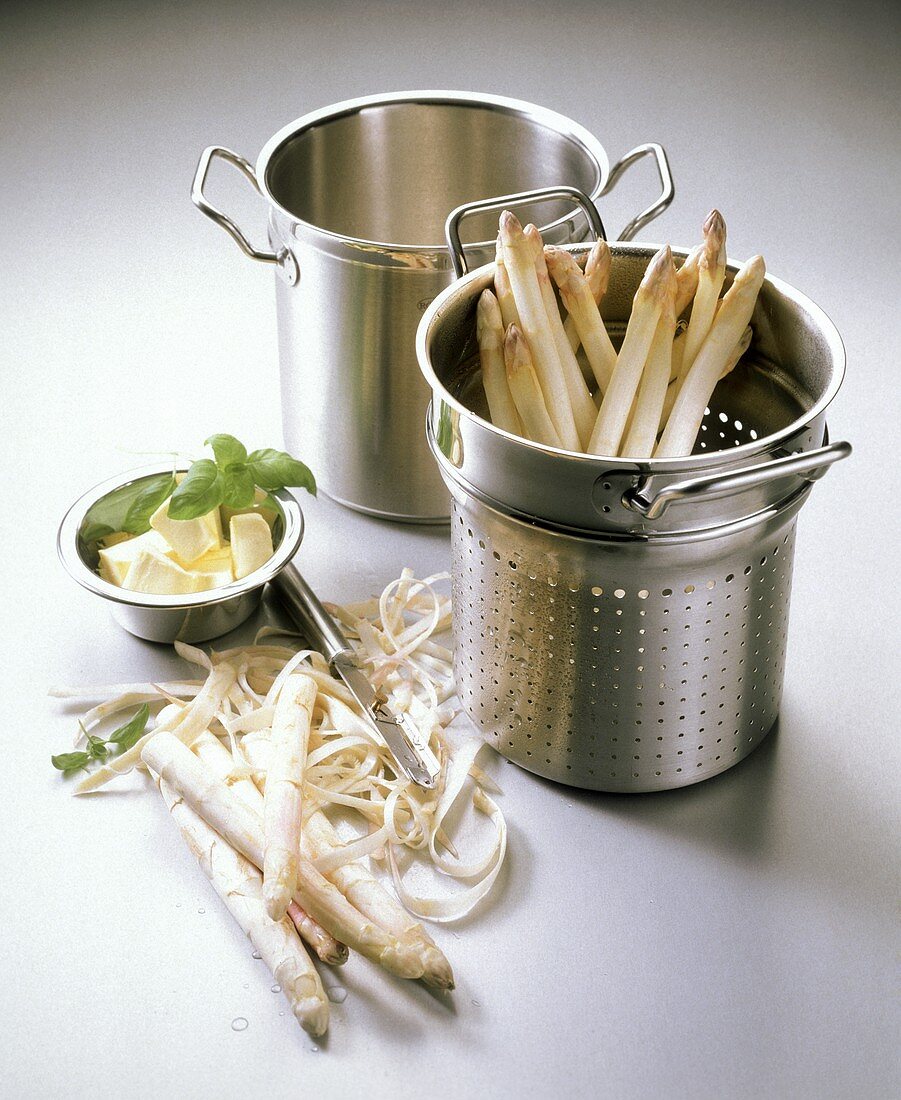 Peeled asparagus in steamer tray, unpeeled spear beside it 