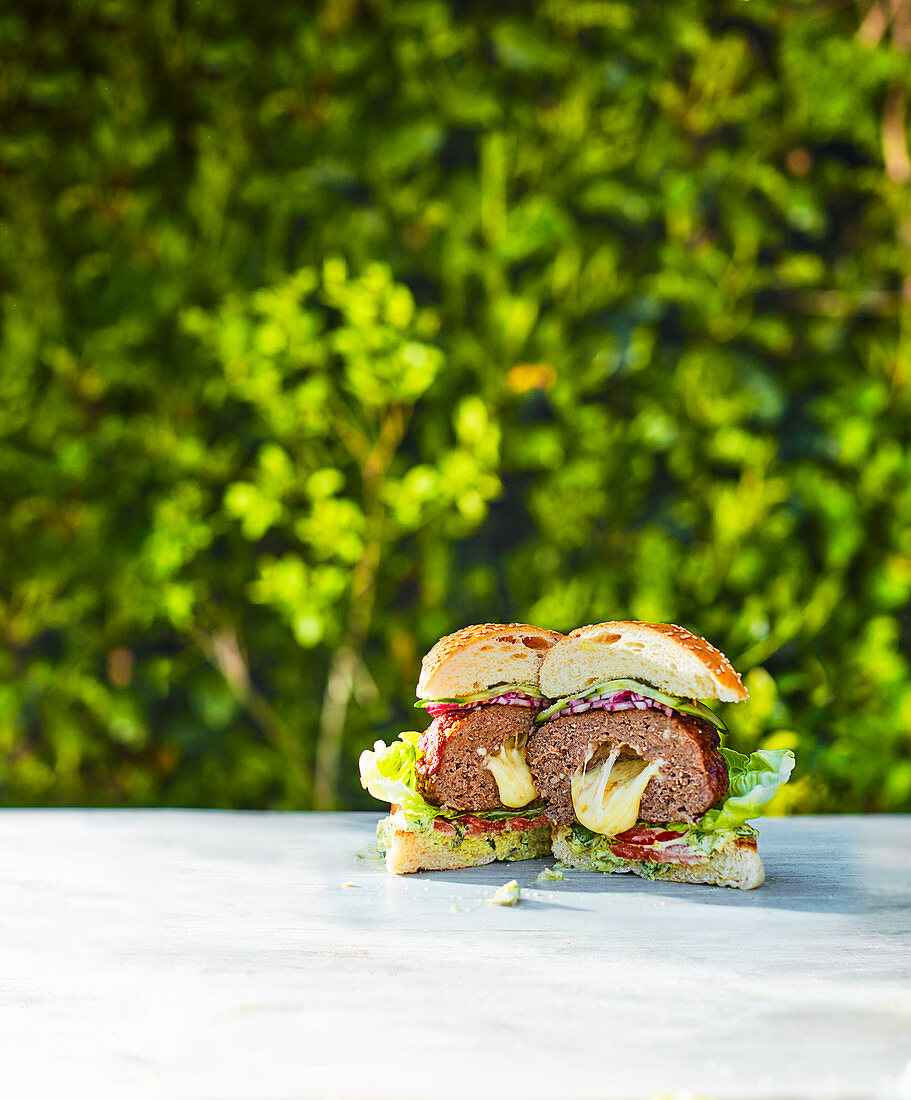 A burger with cheese filling on an outdoor table