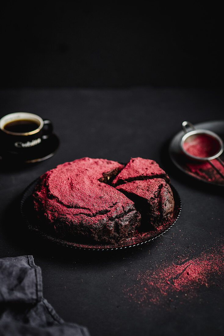 Schokoladenkuchen mit Himbeerpulver vor dunklem Hintergrund