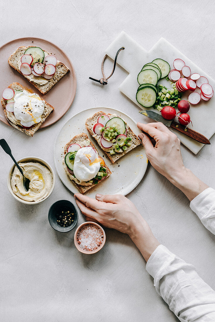 Belegtes Brot mit Hummus, pochiertem Ei, Radieschen und Gurke