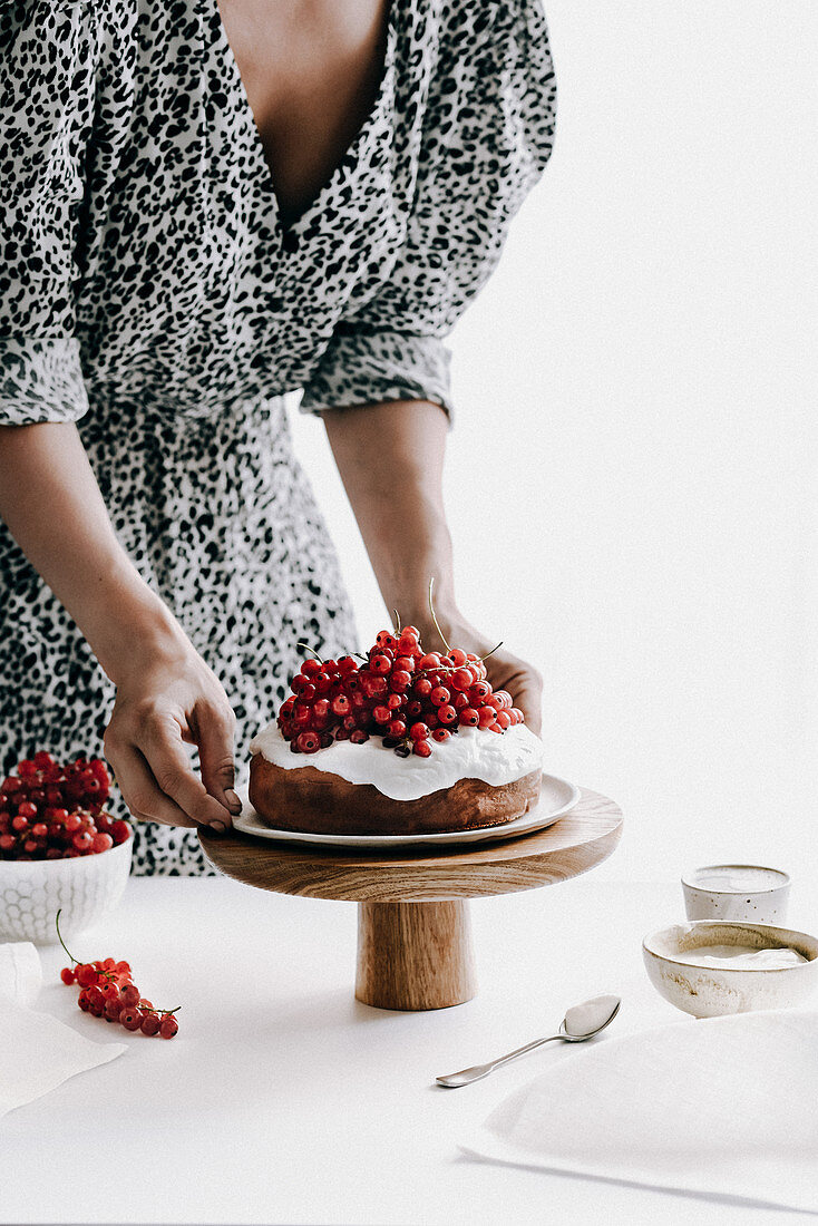 Frau serviert Kuchen mit Ricottacreme und roten Johannisbeeren