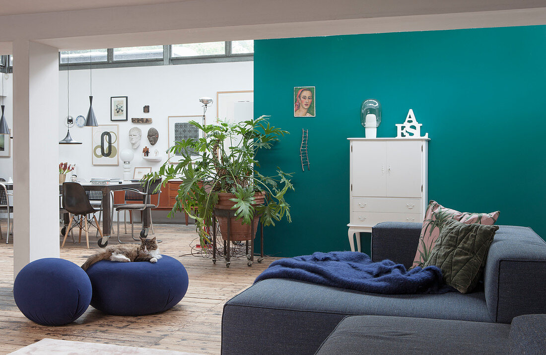 A grey upholstered suite in a lounge area with a turquoise blue wall