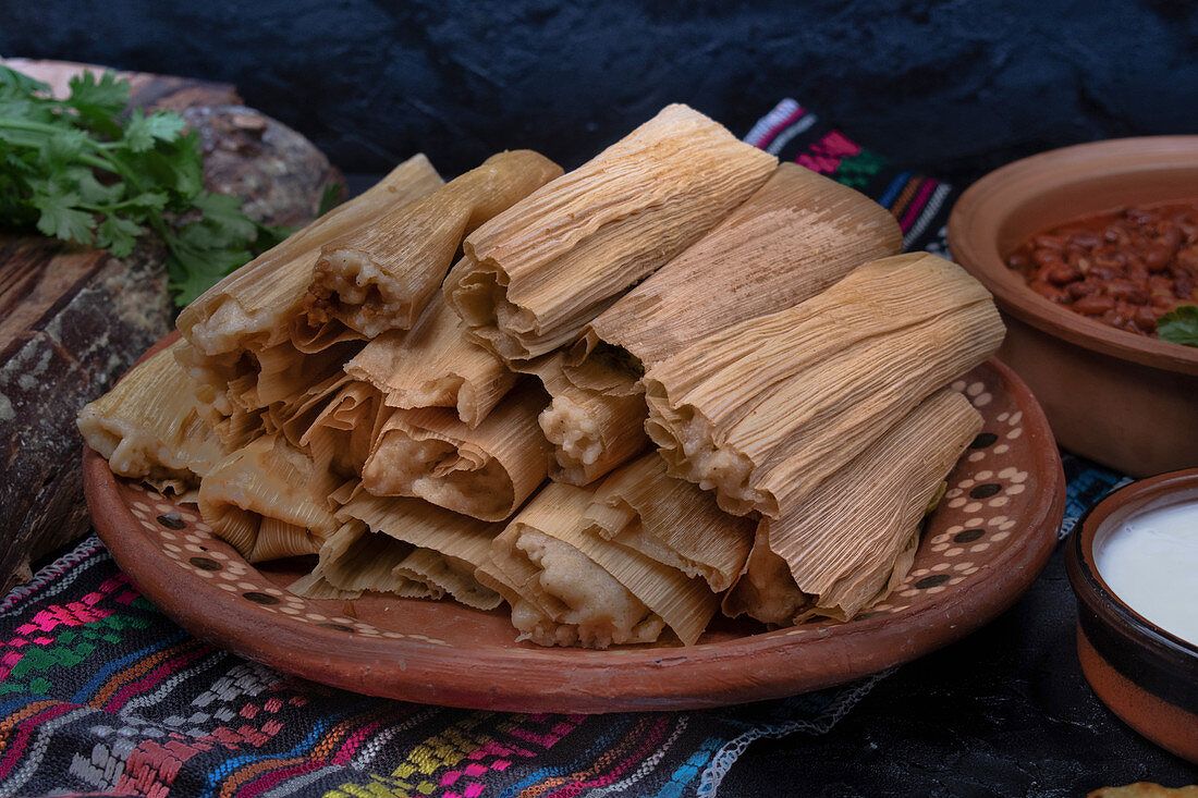 Vegan tamales filled with seitan, masa, chile verde and served with ranchero sauce, cream and chili beans