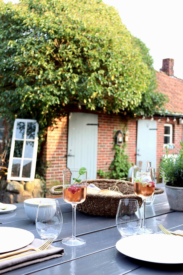 Gedeckter Tisch im sommerlichen Garten mit altem Backsteinhaus