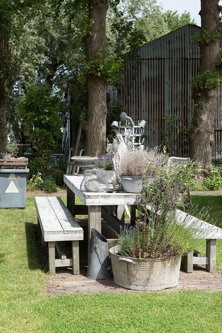 A wooden table with benches and planters in a garden