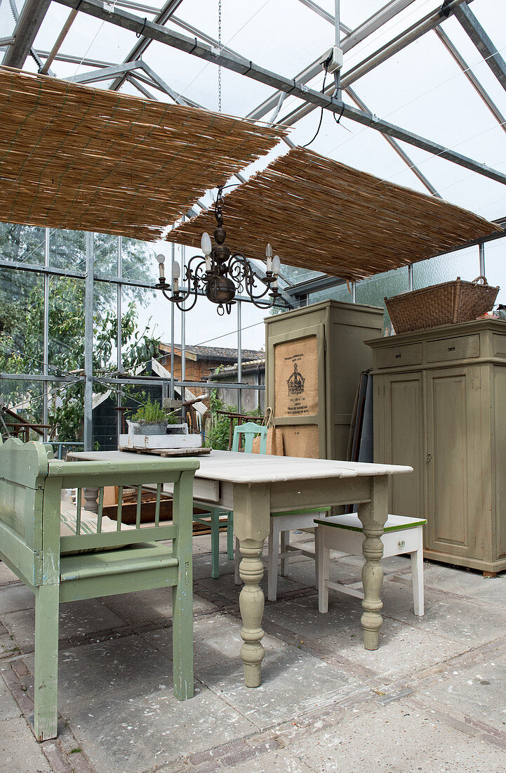 A wooden table and a green bench in a green house