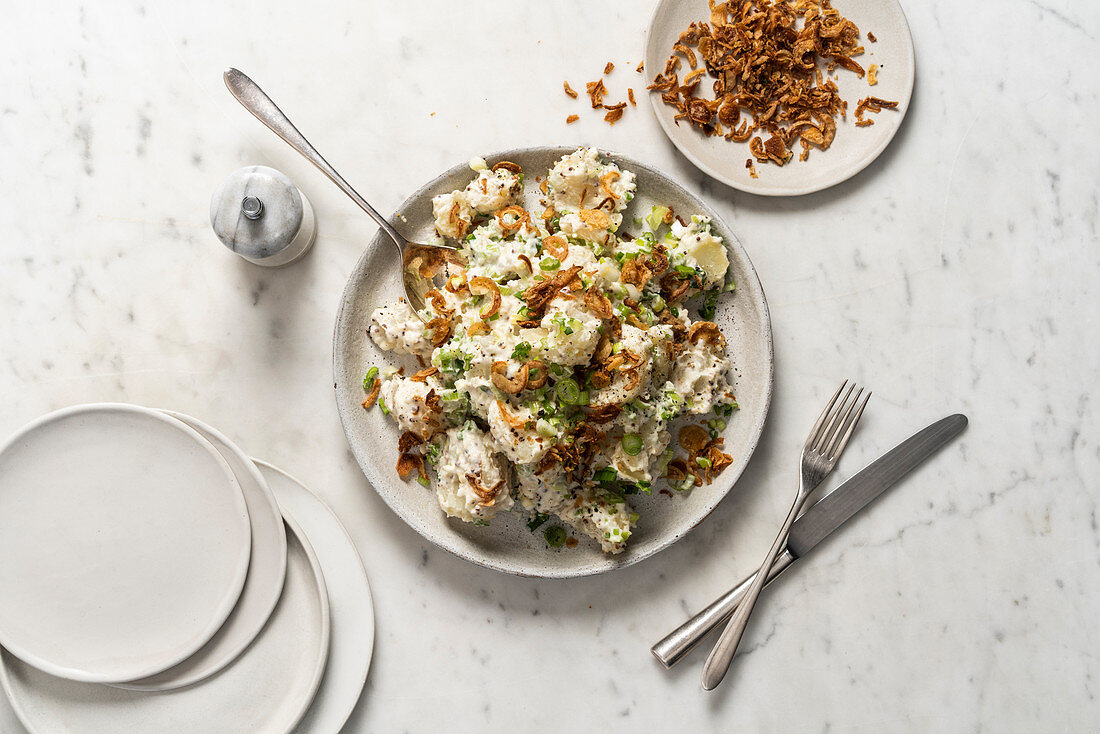 Potato salad with mustard, mayonnaise spring onions and crispy fried onions