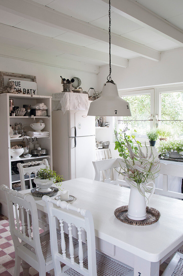 A white table with chairs, an open shelf and a refrigerator in kitchen