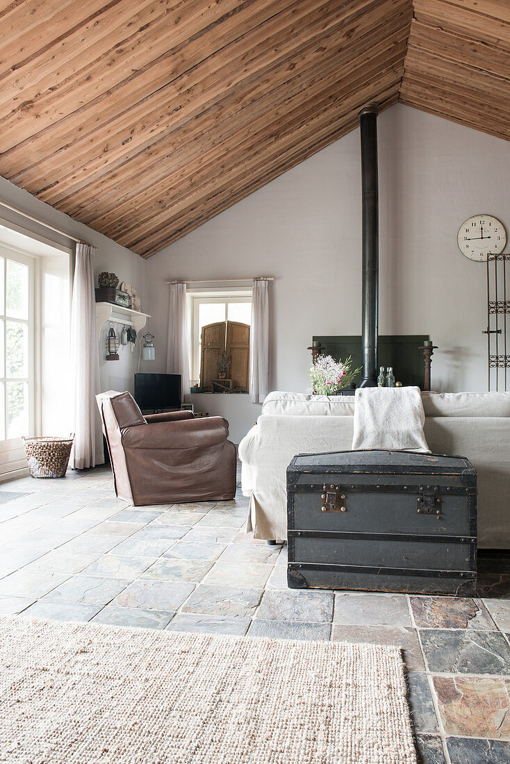 Holztruhe hinter Sofa und Sessel in offenem Wohnraum in ehemaligem Bauernhaus