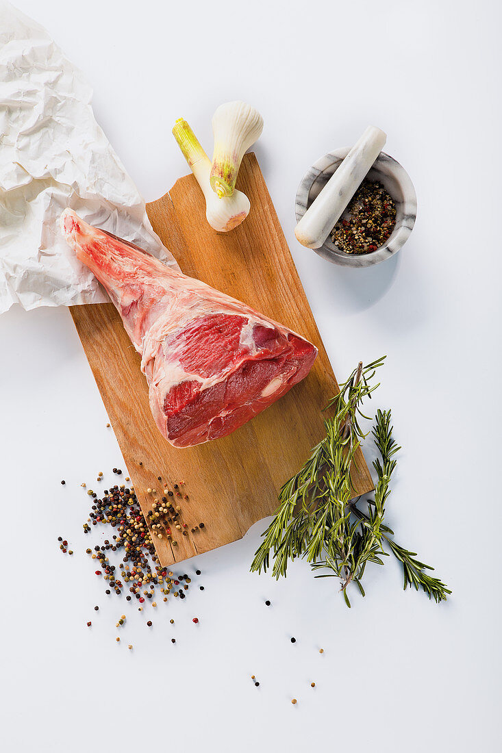 Raw leg of lamb with pepper, rosemary and garlic