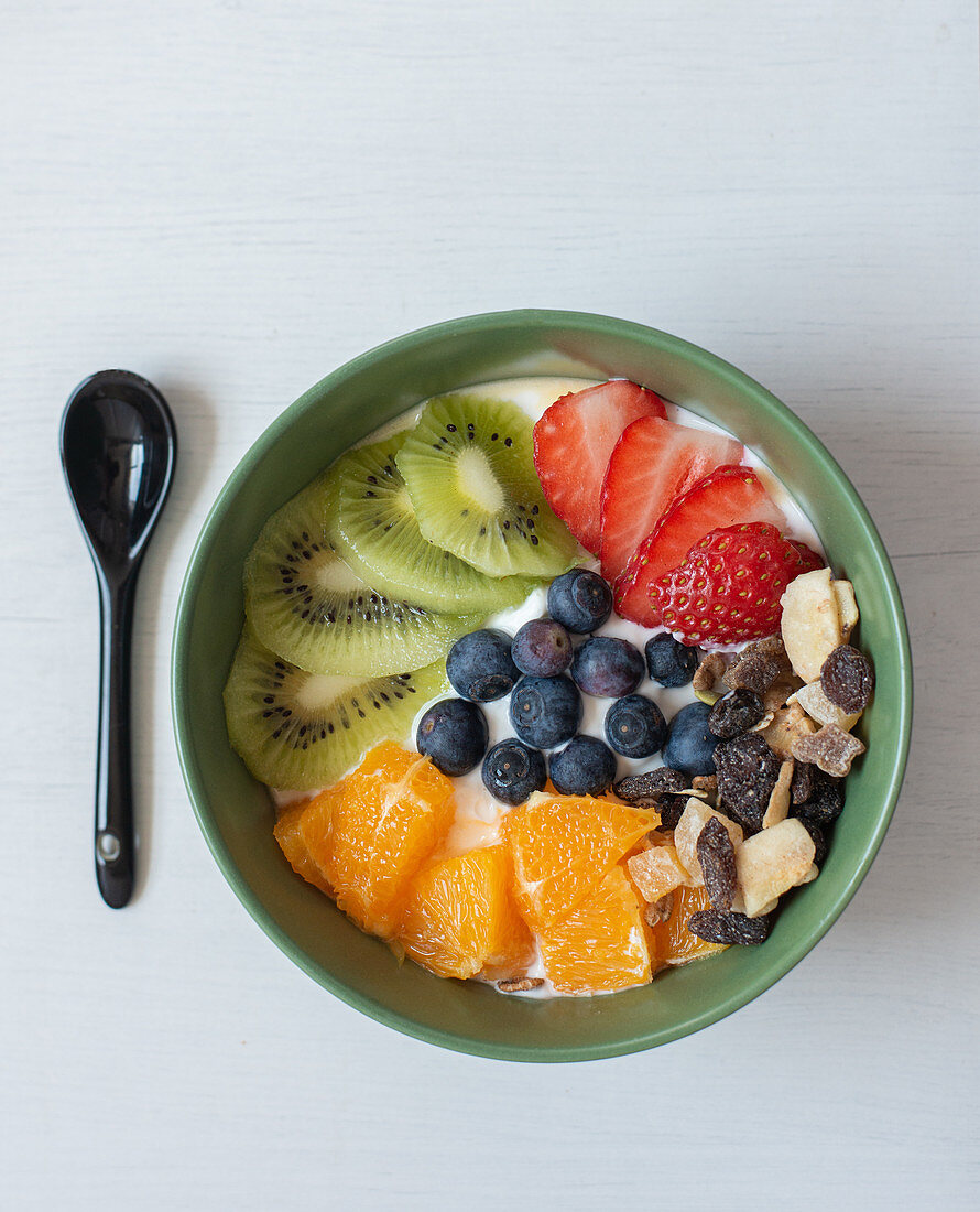 Delicious healthy breakfast with sliced kiwi and oranges placed in bowl with blueberries and strawberries
