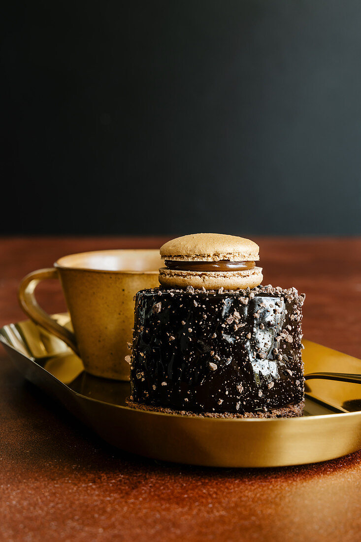 Dark chocolate mirror glaze mousse cake decorated with french macaron