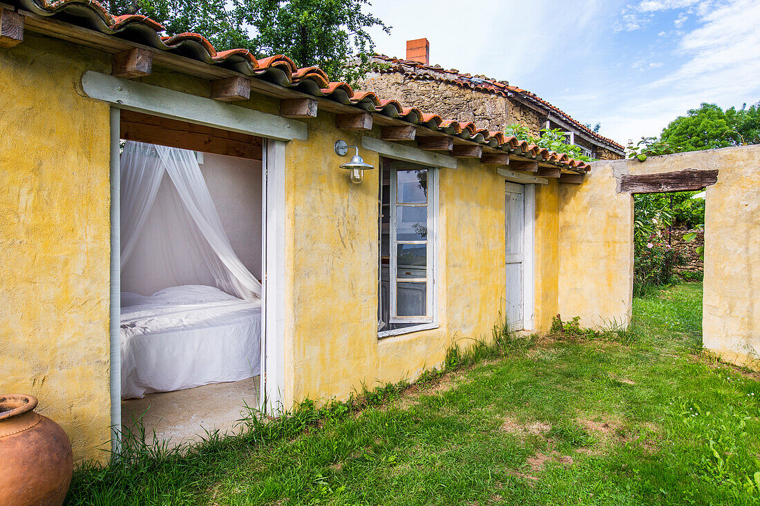 Blick vom Garten ins Zimmer auf Bett mit Baldachin