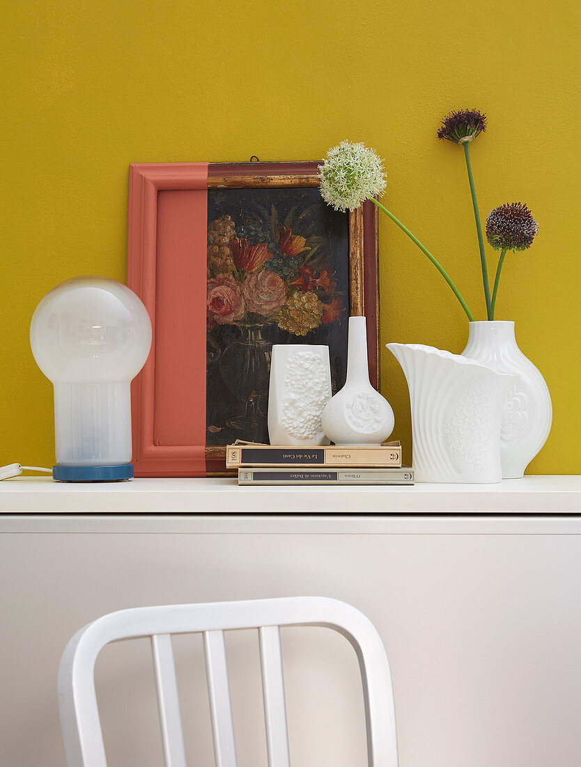 Arrangement of old picture and frame partially painted over and white vases