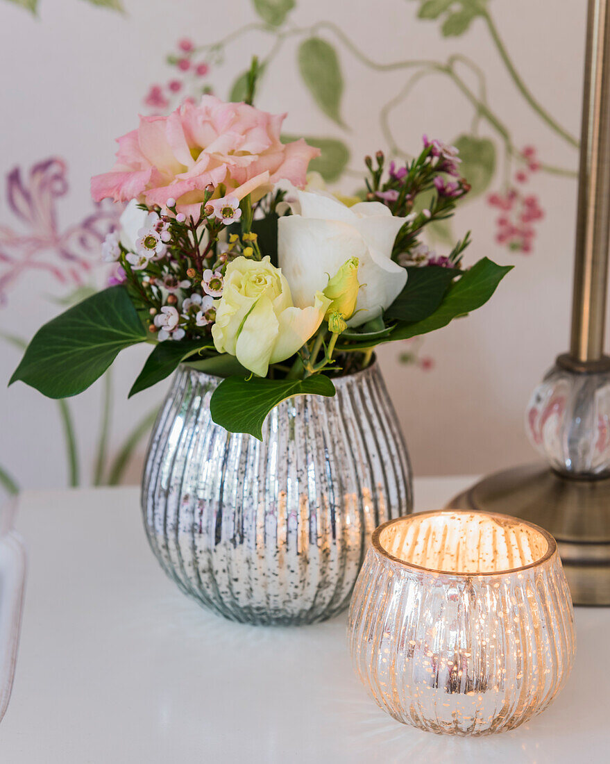 Bouquet of flowers in vintage mercury glass vase and tealight holder