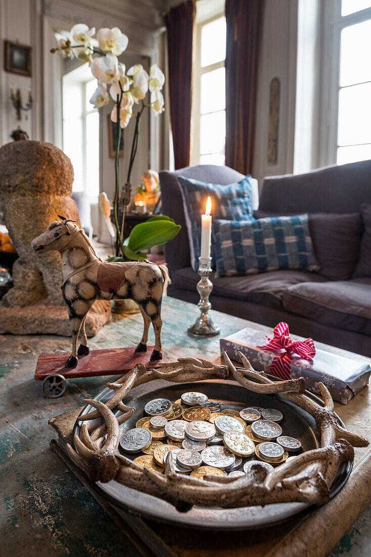 Chocolate money, vintage toys and lit candle on coffee table