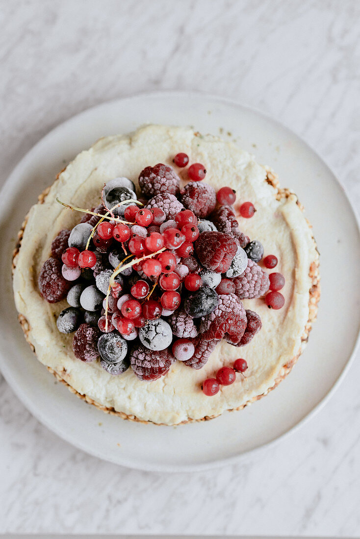 Vegan cake made of expanded millet and dates with cashew cream and fruit