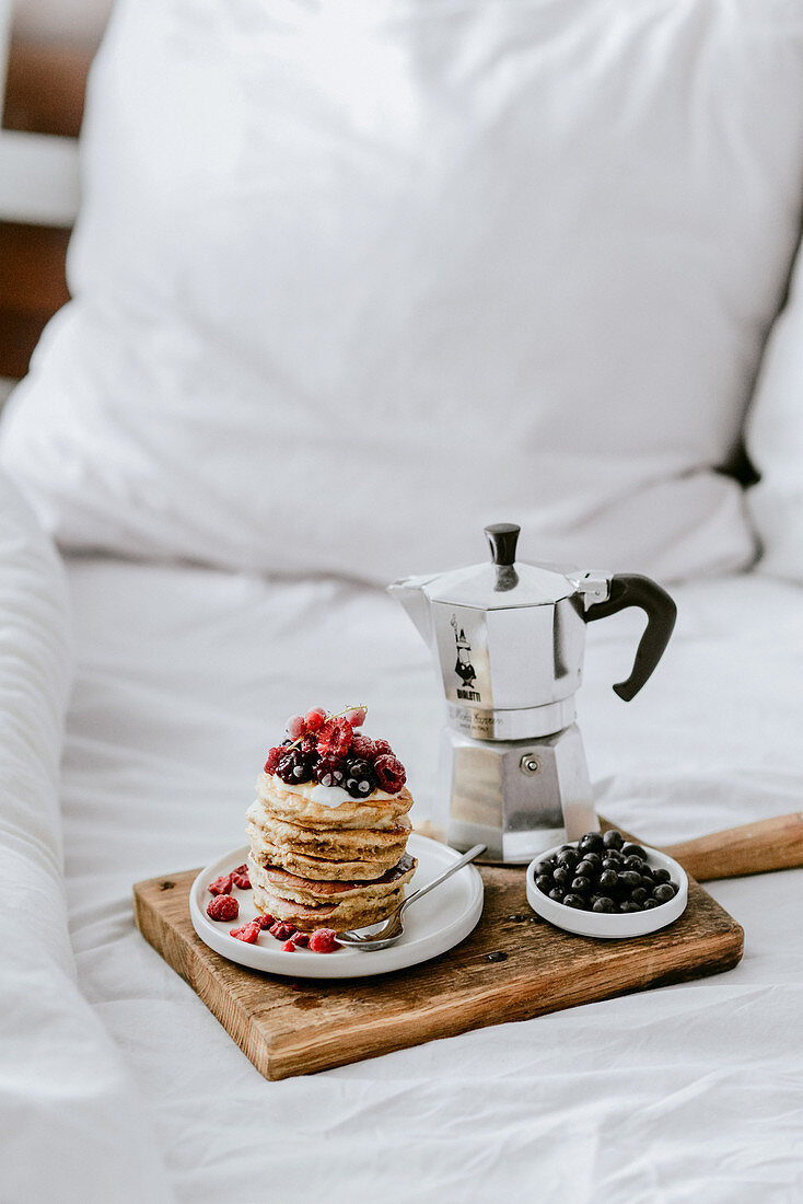 Pancakes mit Beeren und Kaffee als Frühstück im Bett