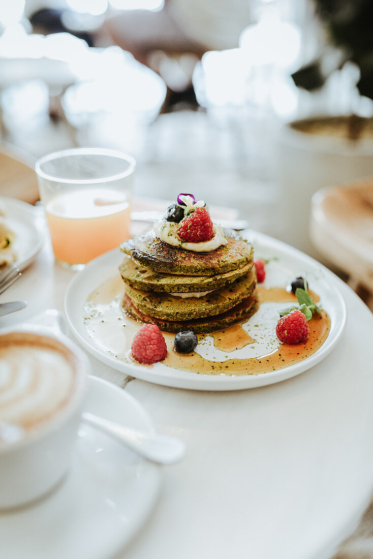 Matcha pancakes with raspberries blueberries and maple syrup