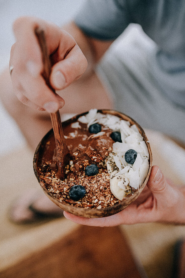 Chocolate bowl with blueberry muesli and coconut flakes