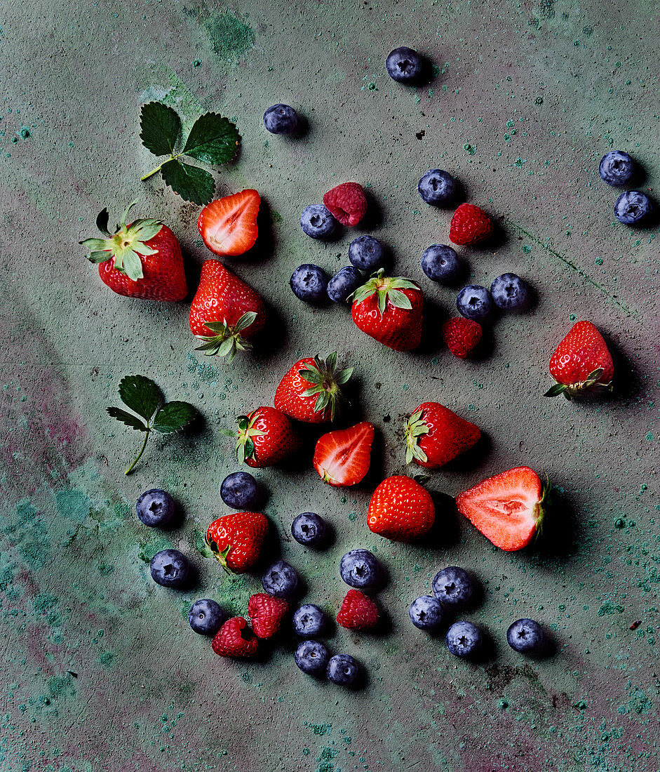 Strawberries, raspberries and blueberry on a concrete surface