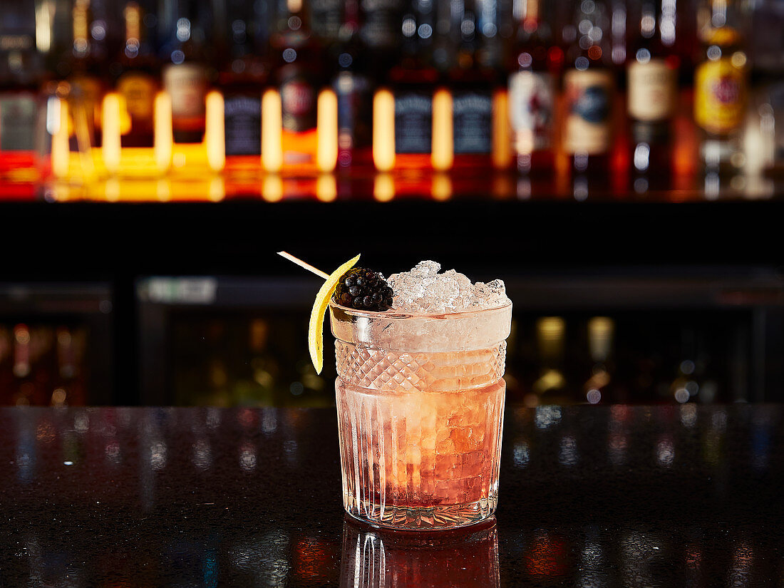 Cocktail mit Brombeere und Crushed Ice in einer Bar