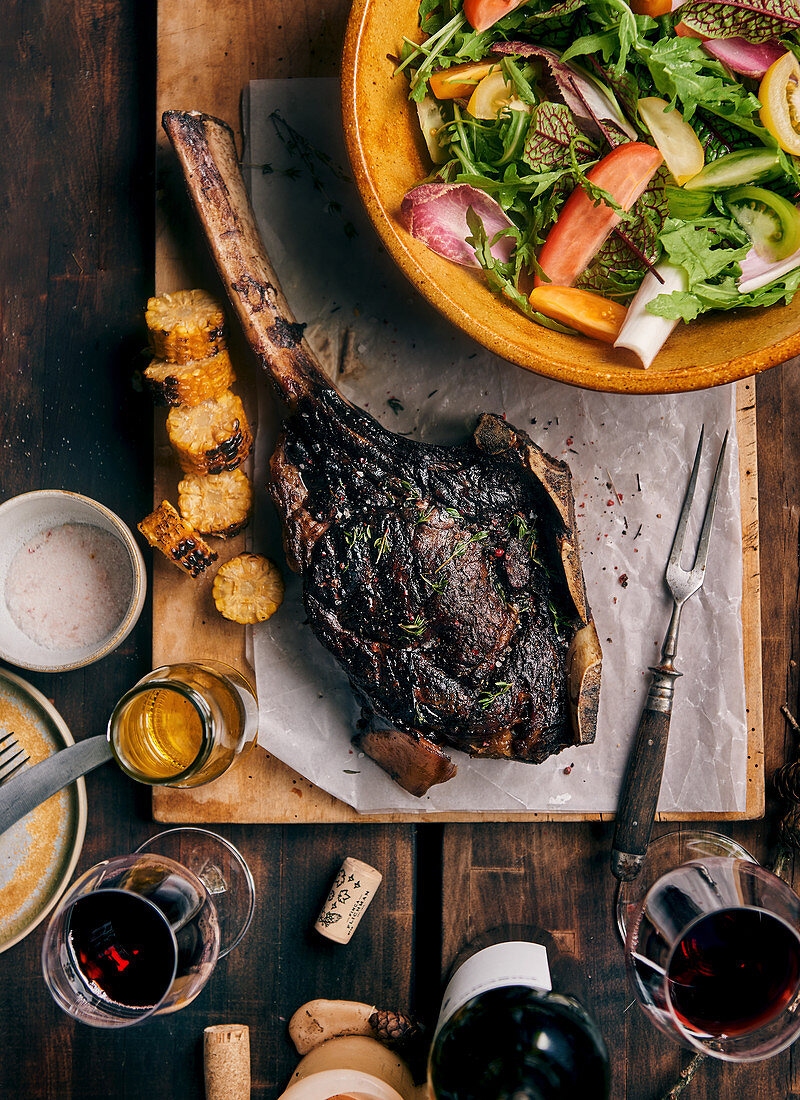 Grilled tomahawk steak on a wooden board with salad