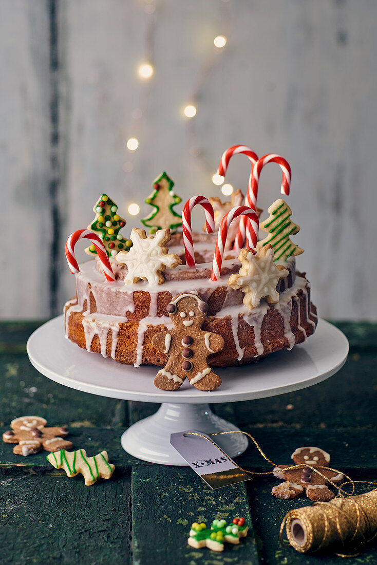 A Bundt cake with lemon glaze decorated with butter biscuits, candy canes and gingerbread men