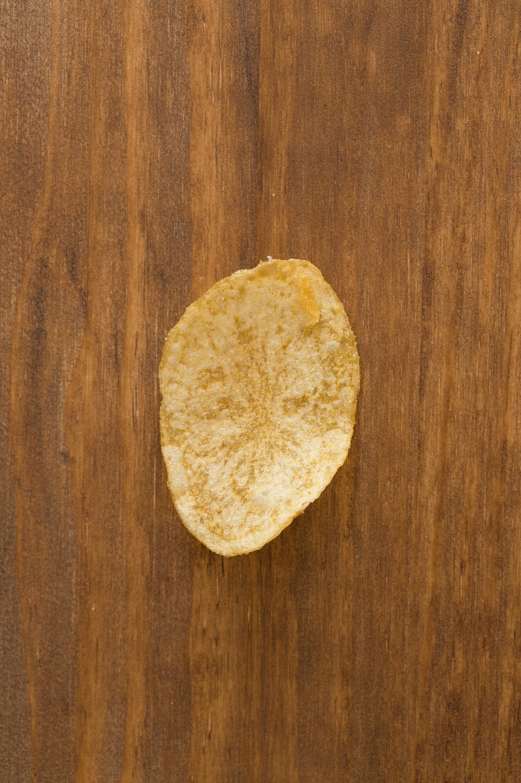 A crispy potato chip on a wooden background