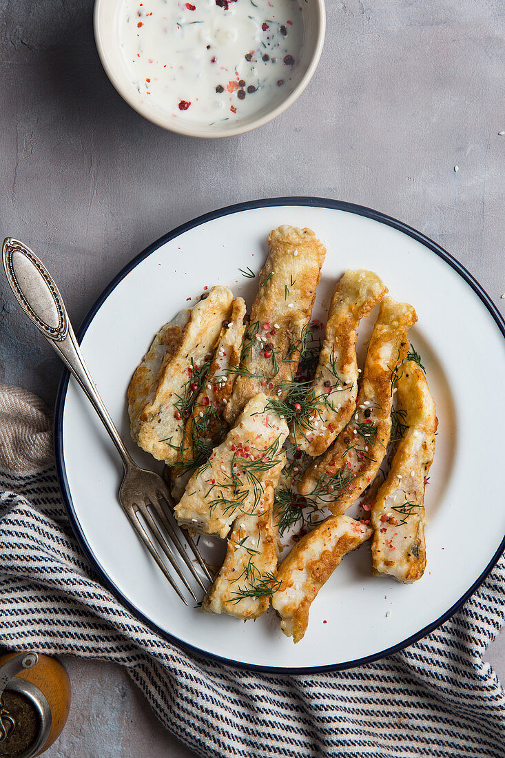 Roasted fish with dill and pink pepper placed on table