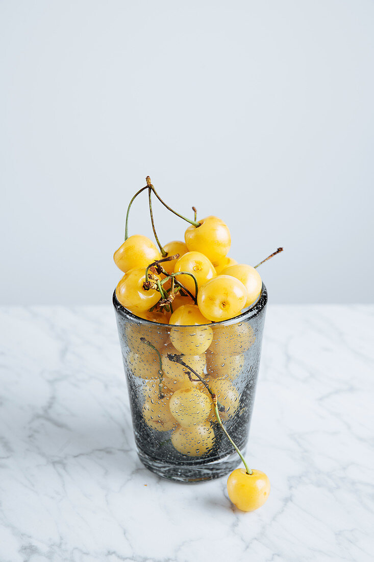 Frische gelbe Kirschen im Glas auf Marmortisch