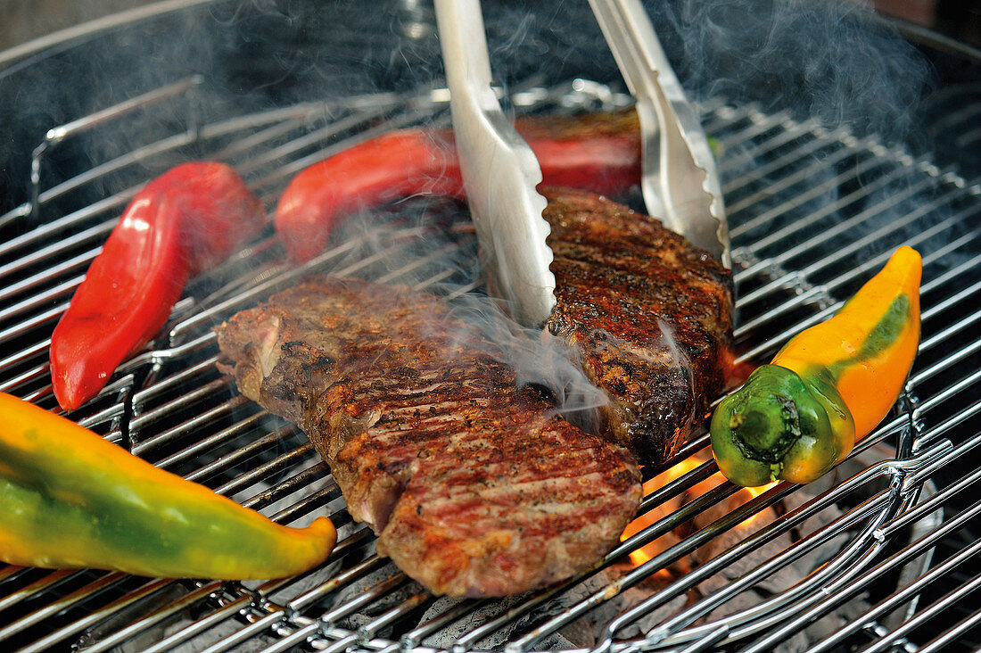 Beef steaks and pointed peppers on a grill