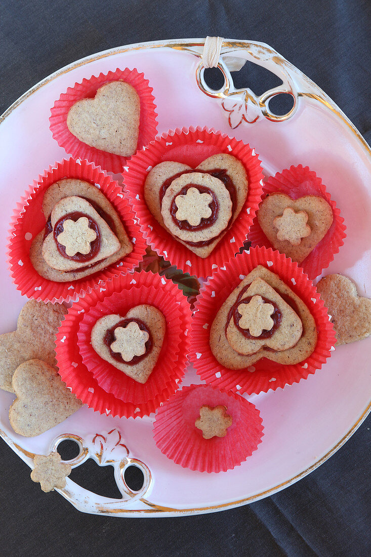 Herzförmige Plätzchen mit Marmelade in roten Muffinförmchen