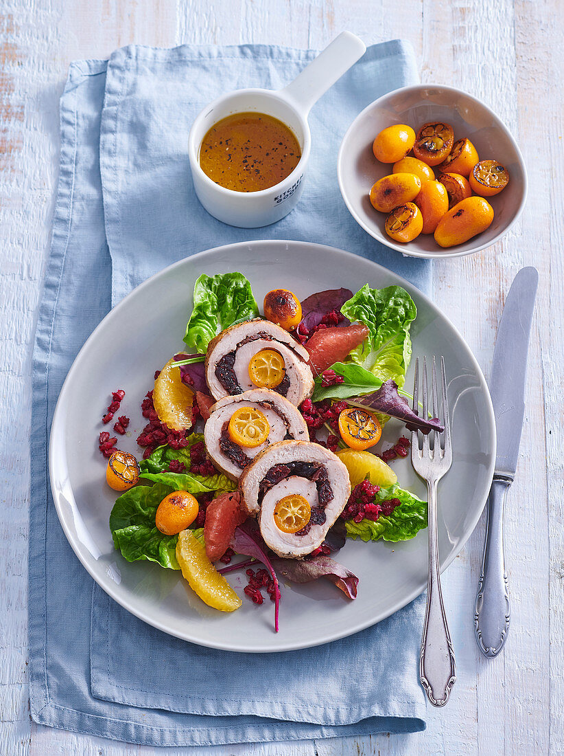 Pork roll with kumquats and cranberries on a salad with pearl barley