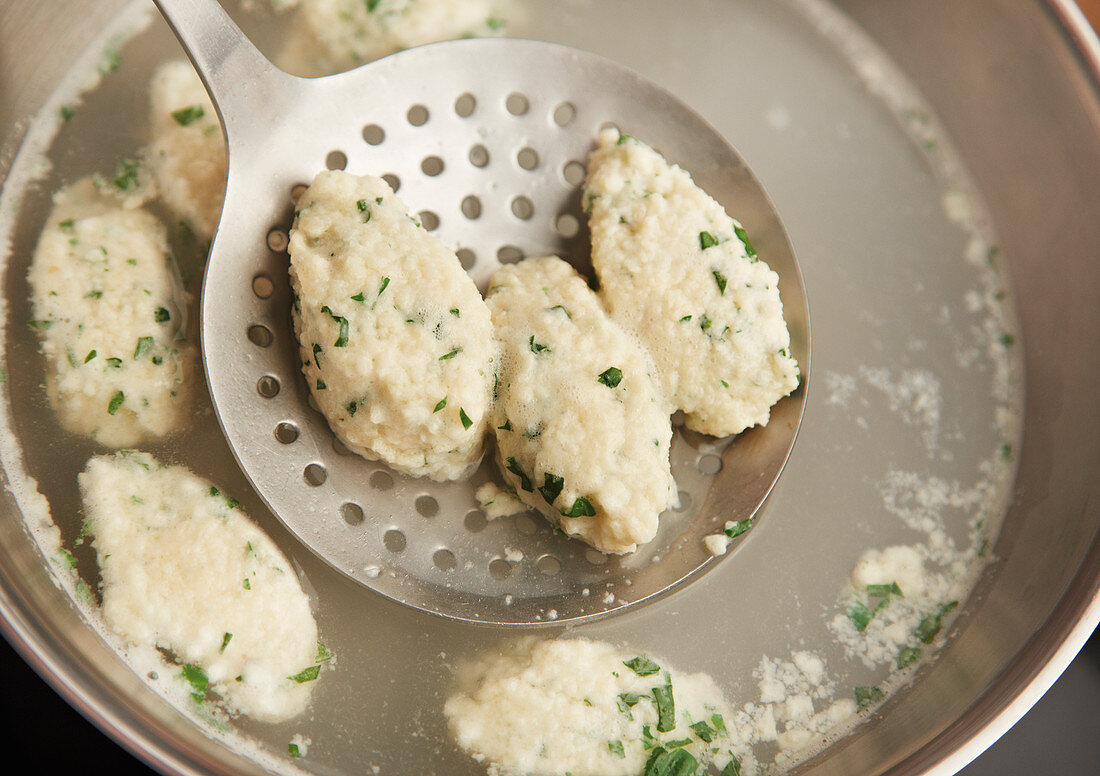 Cooked quark dumplings being removed from a pot