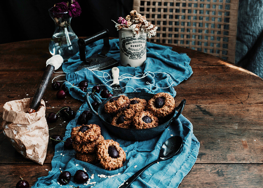 Yummy baked cherry cookies placed on wooden table with piece of cloth and vintage iron