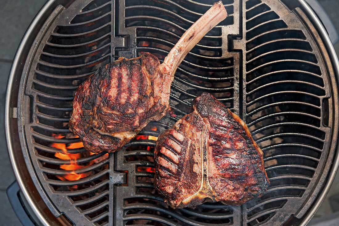 Tomahawk steak and porterhouse steak on a grill rack