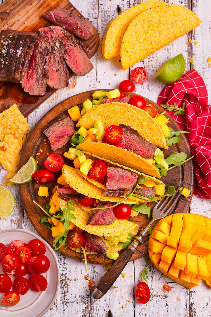 Taco-Shells mit Rindfleisch, Avocado, Mango, Rucola und Kirschtomaten