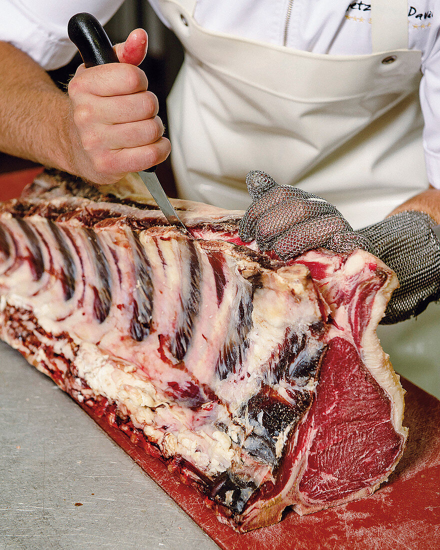 A butcher carving a side of beef