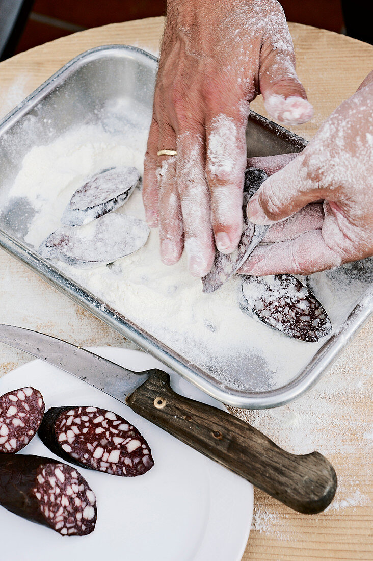 Slices of black pudding being dusted in flour