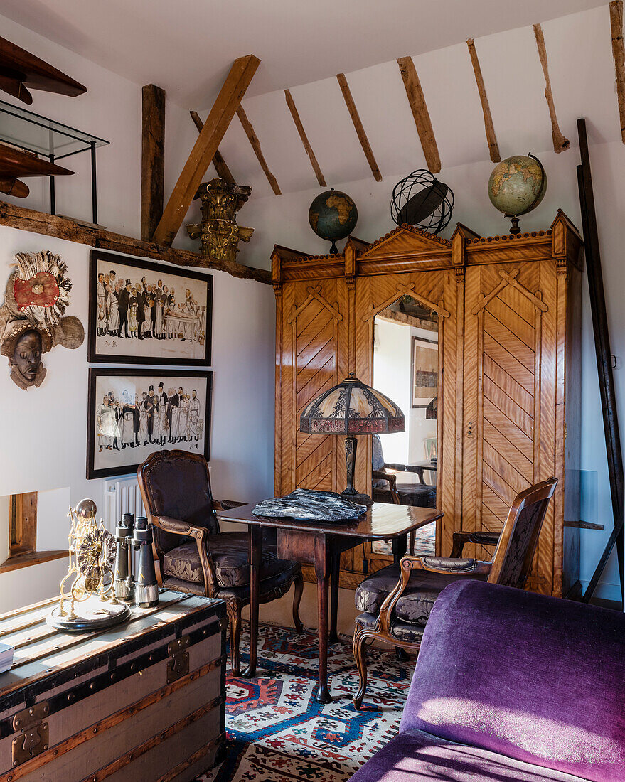 German cupboard topped with several 18th and 19th century globes, an early Caucasian kilim softens the floor, writing table