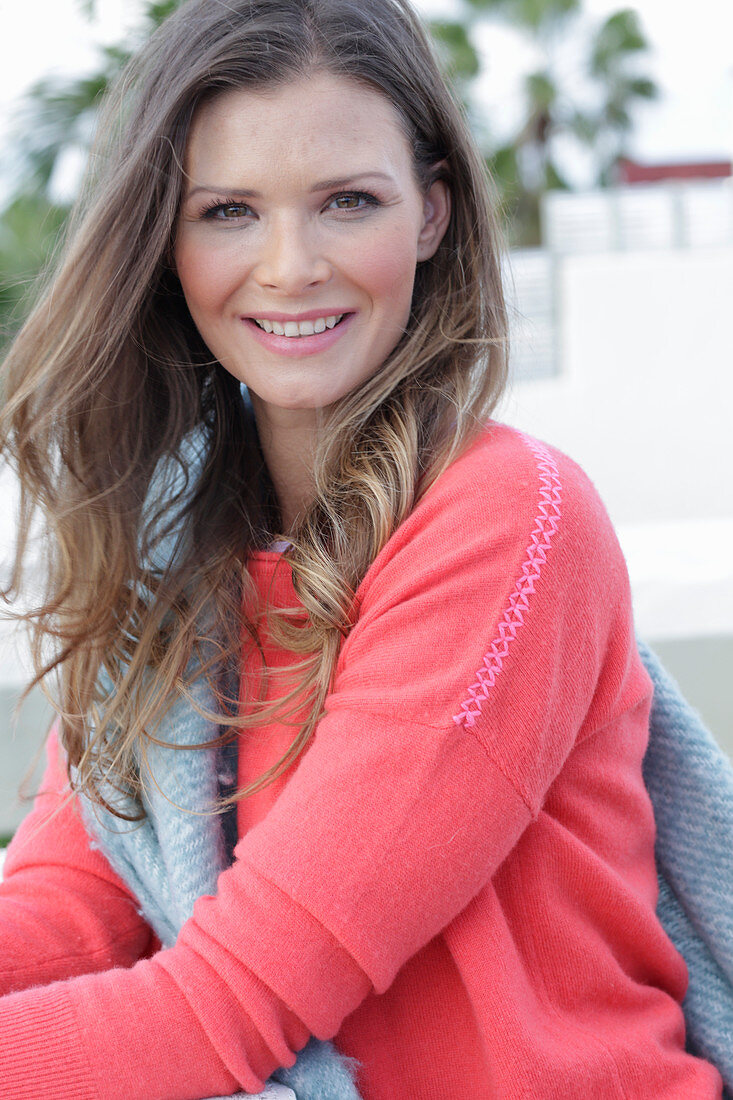 A young woman wearing a coral jumper