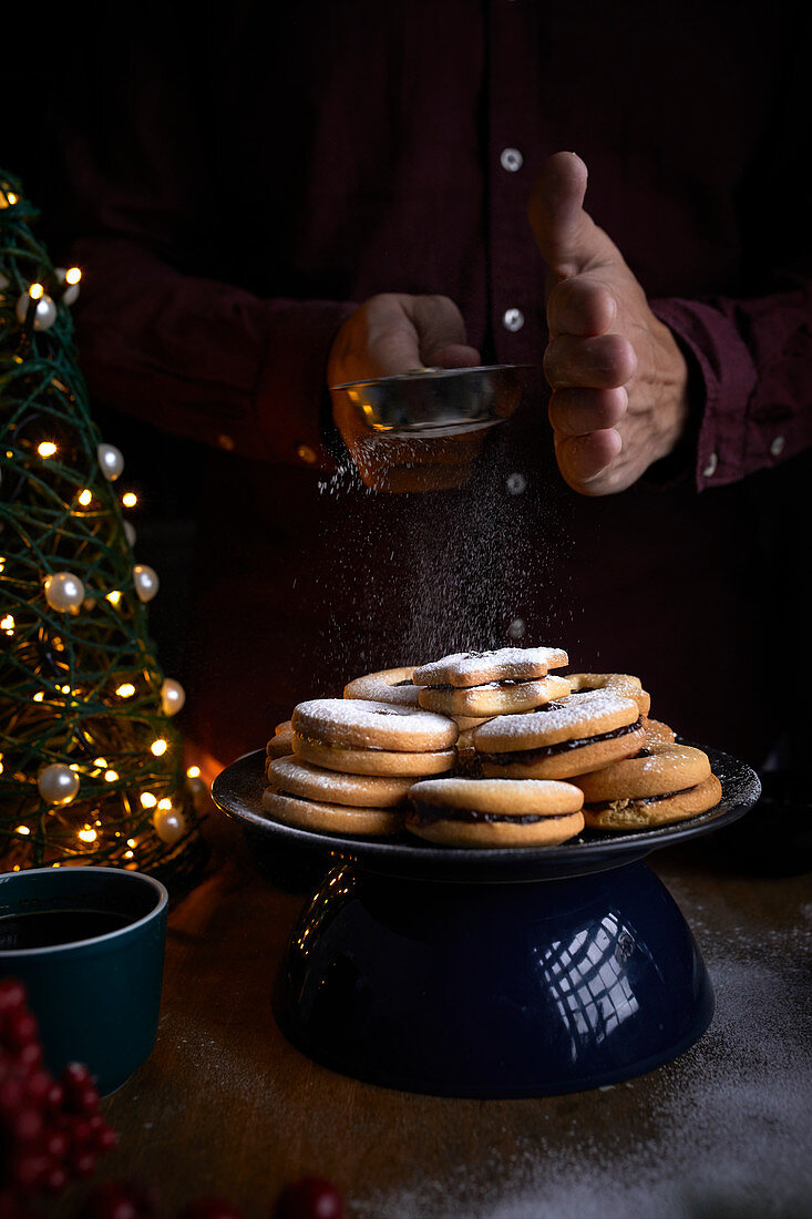 Freshly baked Linzer cookies being dusted with sugar