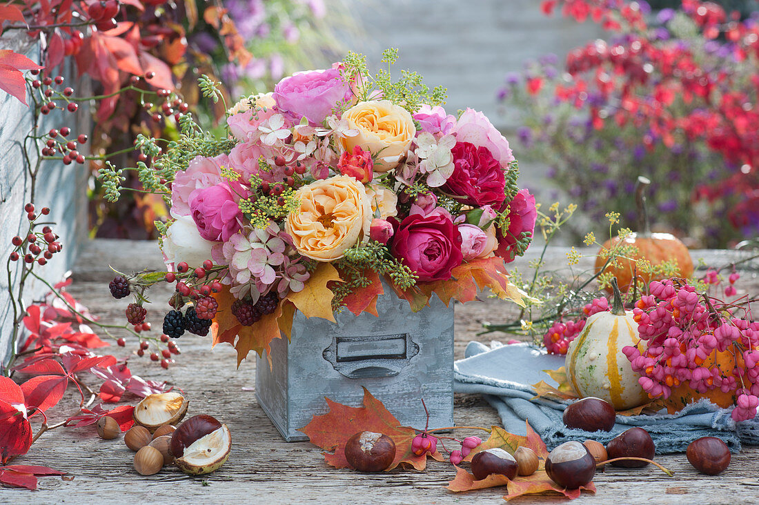 Autumn bouquet of roses, hydrangea, fennel, rose hips, blackberries and autumn leaves, chestnuts, pumpkins, and common spindle as decoration