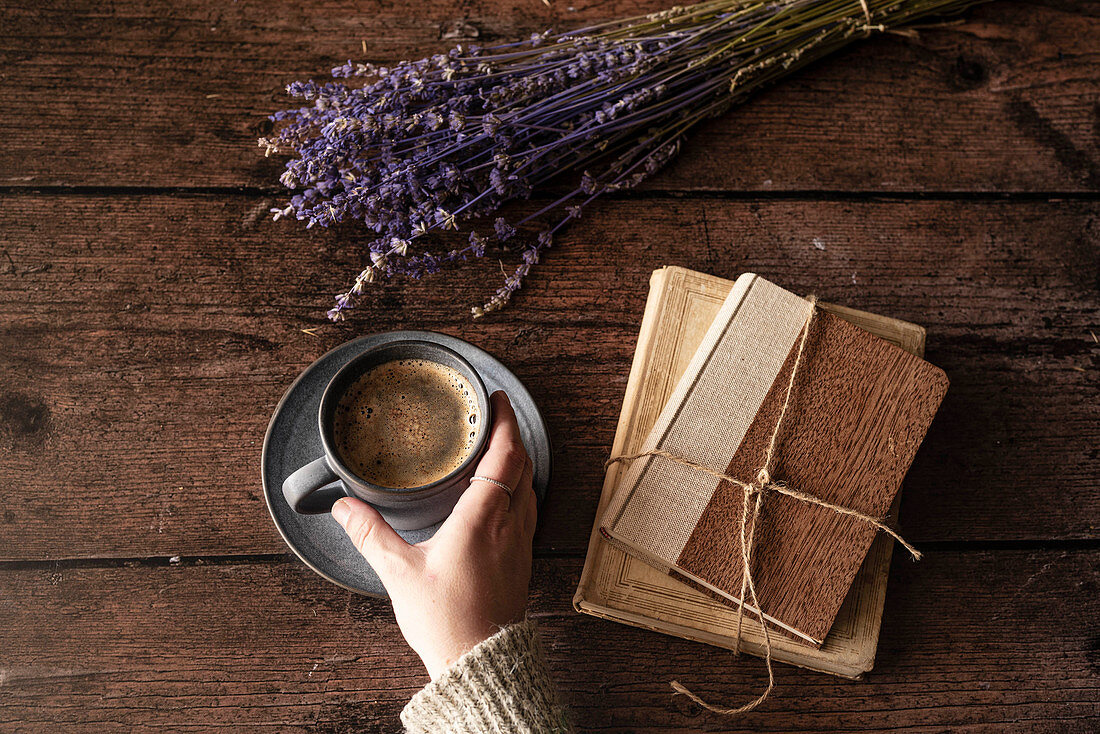 Kaffee, Bücher und Lavendelblüten auf Holzuntergrund