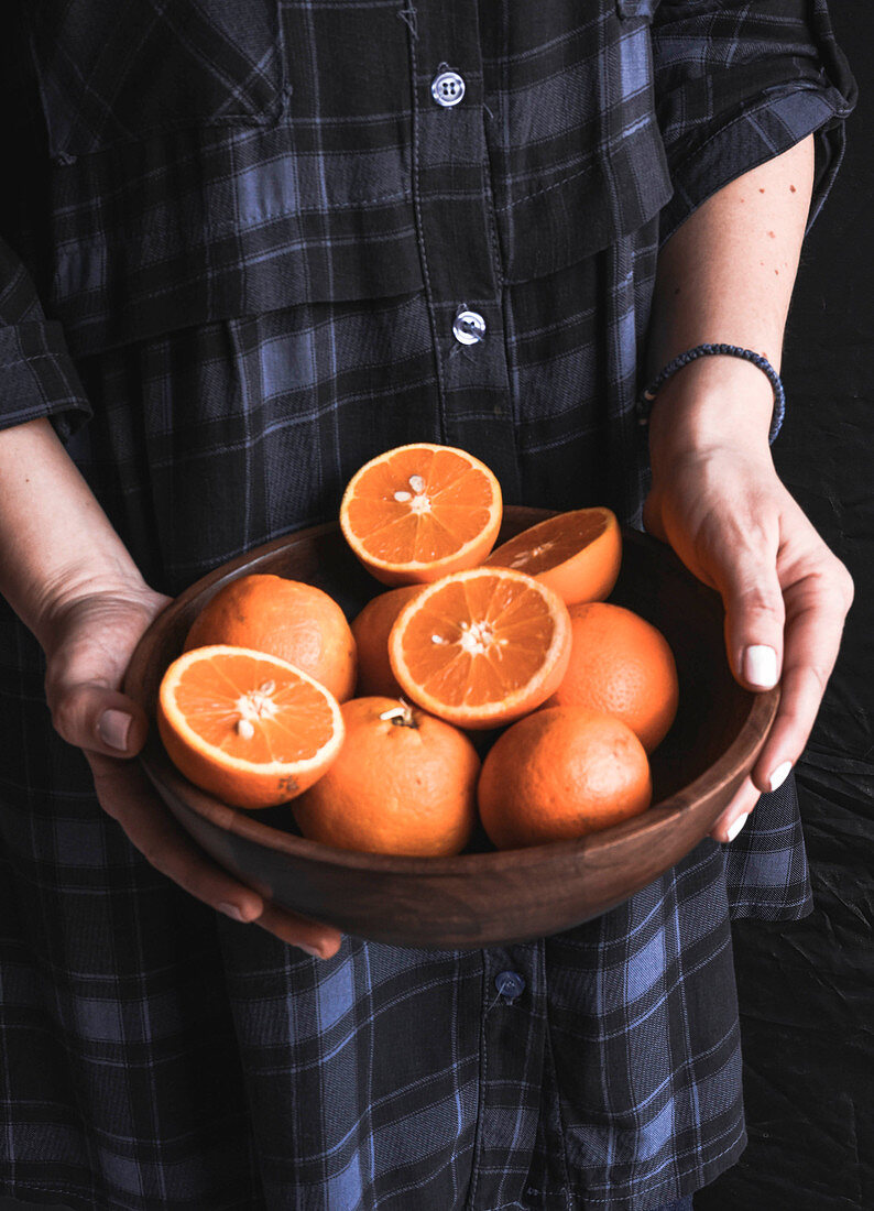 Woman holding bowl with oranges