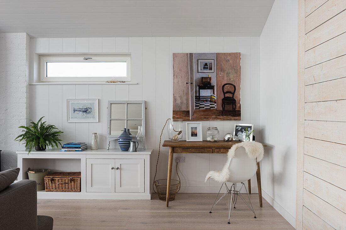 Artwork above wooden desk with sheepskin on chair