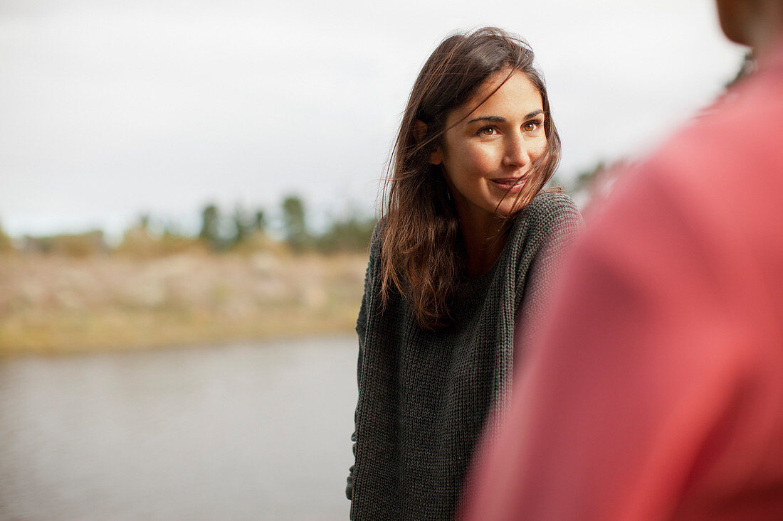 Smiling woman looking at man at lakeside