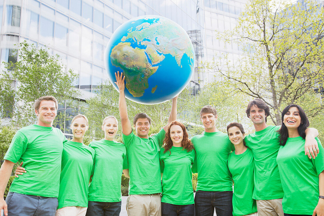Team in green t-shirts lifting globe
